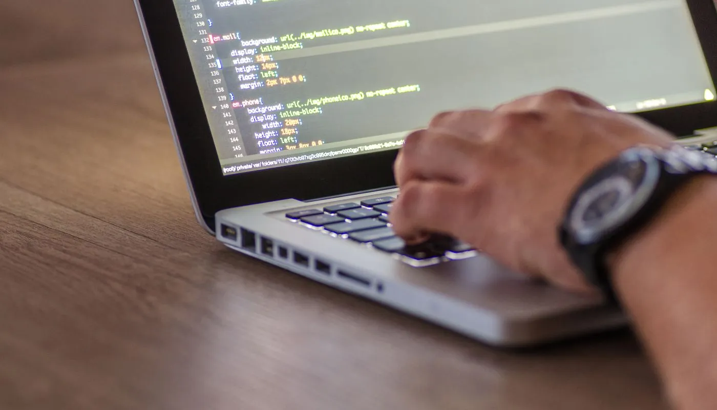 Developer writing software code on a laptop, representing the digital product engineering services R Systems provides.